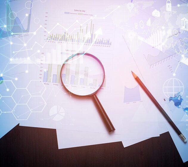 Magnifying glass and documents with analytics data lying on table Magnifying glass and documents with analytics data lying on table